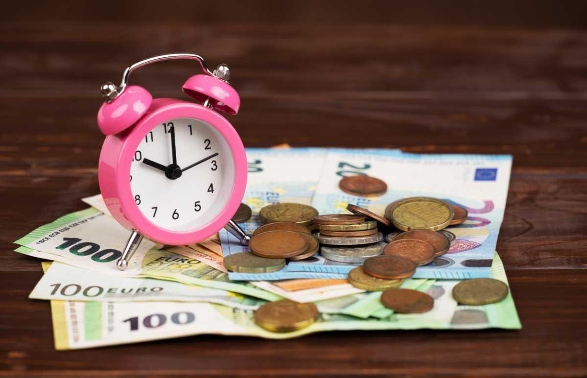 Wecker der auf einem Haufen Geld steht
