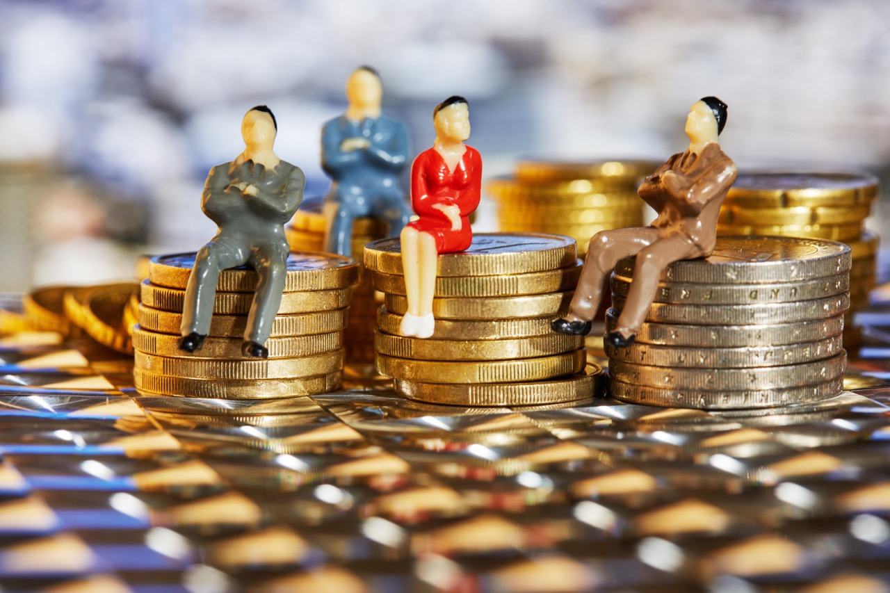 Modelfiguren sitzen auf kleinen Stapeln aus 1-Euro-Münzen