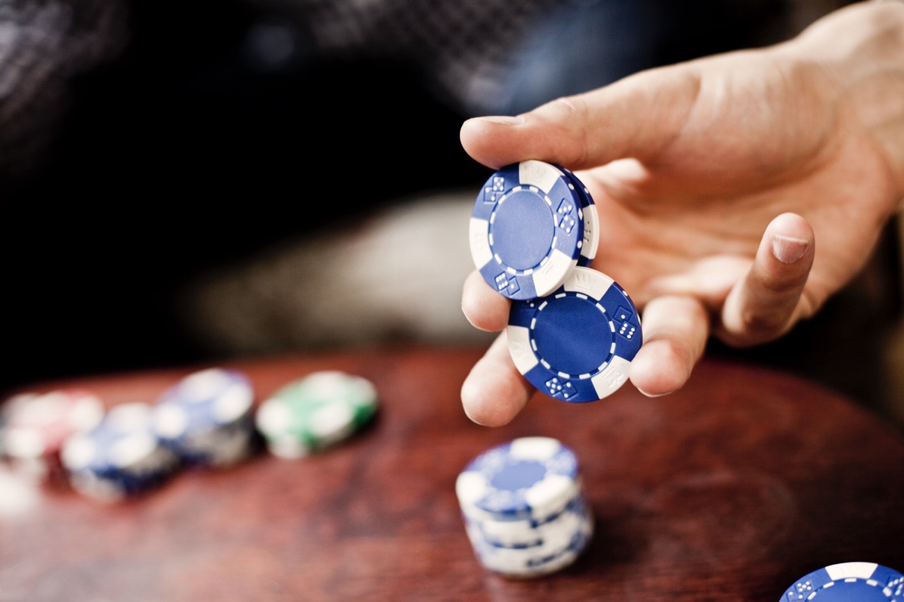 Mann hält zwei blaue Poker Chips in der Hand