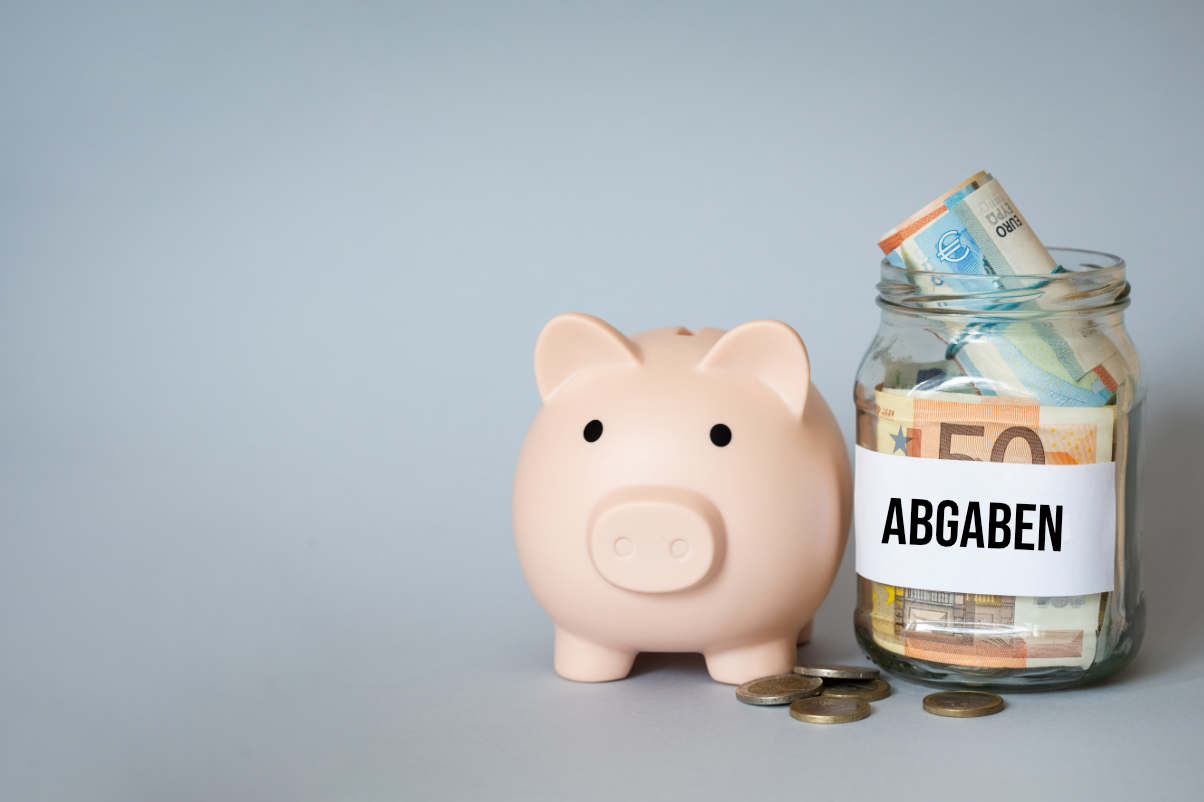 Sparschwein und daneben ein Glas mit Geld für Abgaben